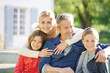 © goodluz - Portrait of happy family of four sitting on bench