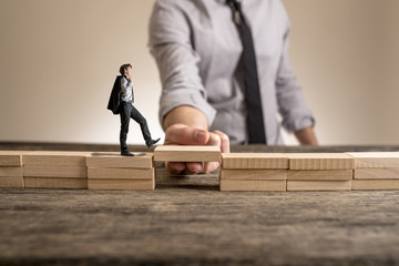 Little businessman walking across bridge