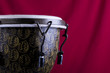 Image of a handmade wooden bongo drum on a red background.