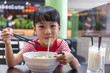 Leinwandbild Motiv Asian little Chinese girl eating noodles soup