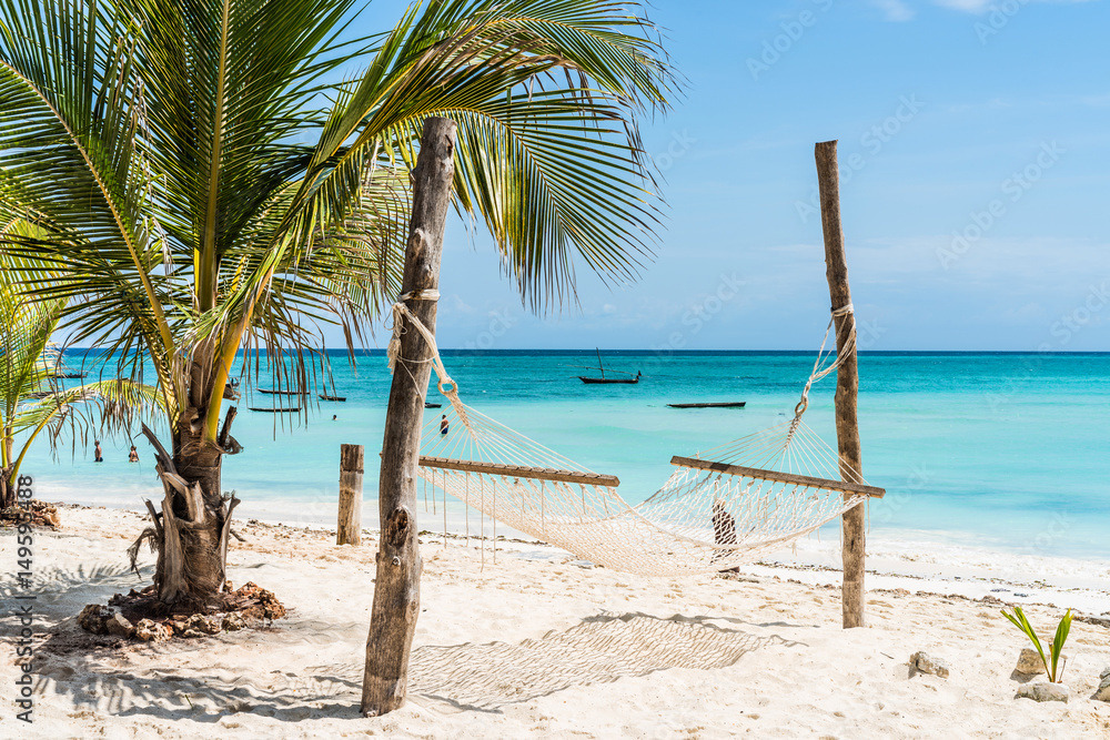 beautiful view of palm and hammock on Zanzibar beach with blue sky and ocean on the background - obrazy, fototapety, plakaty 