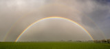 Fototapeta Tęcza - Rainbow in the sky above the spring field after the storm