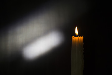 Burning candle on black background