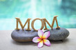 Mother's day concept background, mom wooden text on spa stone with space on blurred swimming pool background