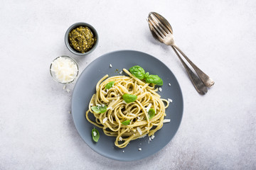 Homemade linguine pasta with green pesto and basil. Italian healthy food concept with copy space, top view.