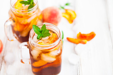 Homemade lemonade with ripe  peaches and fresh mint. Fresh peach ice tea on white wood table. Copy space background.