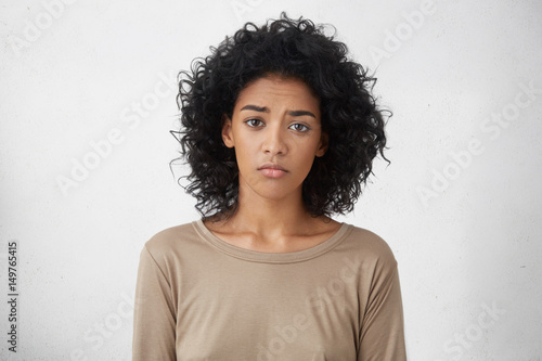Fotomural Attractive upset young dark skinned lady with Afro hairstyle feeling sad or bored expression while spending weekend at home, looking unhappy after friends forgot to invite her to party