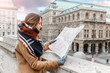 © EdNurg - A stylish woman in a coat with a scarf is guided by a map in the center of a European city, the concept of travel
