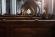 A believing woman sits on a bench in the church and prays to God with hands clasped