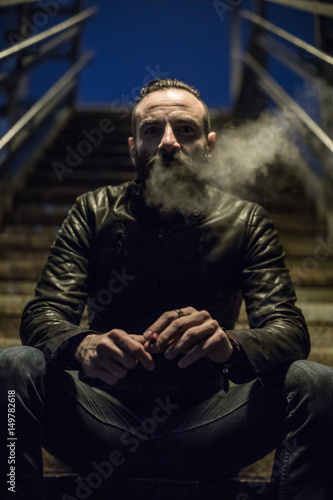 Photo  A portrait of a tough, bearded man lighting a cigarette in the streets of Brooklyn, New York City