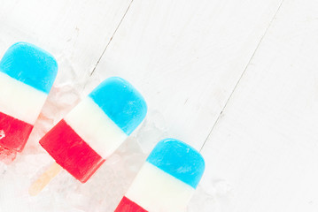 ICe cream. Patriotic Red White Blue Popsicles for 4th of July holiday, on white wooden table. copy space top view