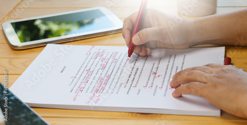 Fotomural hand holding red pen over proofreading text