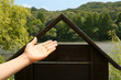 Hand Presenting Wooden House, River View Outdoors 