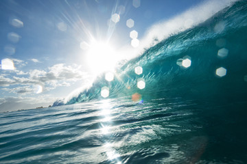 Wall Mural - surfing wave with bright sun and light bokeh on water drops