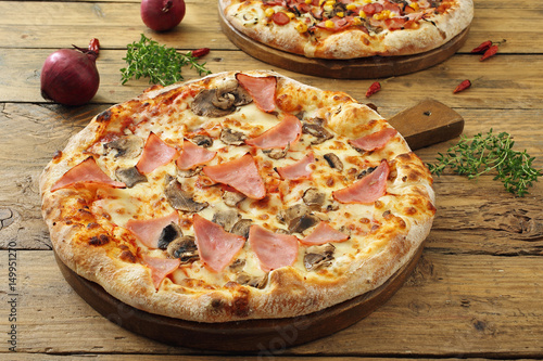 Fotomural pizza con prosciutto e funghi sfondo tavolo rustico