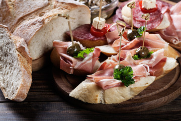 Sticker - Spanish tapas with slices jamon serrano, salami, olives and cheese cubes on a wooden table