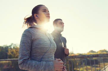 Wall Mural - happy couple with earphones running outdoors