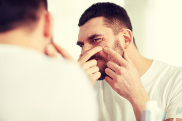 Canvas Print - man squeezing pimple at bathroom mirror