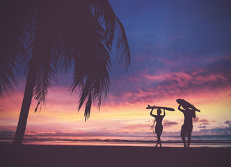 Silhouette Of surfer people carrying their surfboard on sunset beach