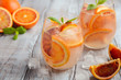 Cold refreshing drink with blood orange slices in a glass on a wooden background, selective focus.