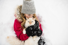 Portrait Of Green Eyed White Cat Hugged By Girl In Snow