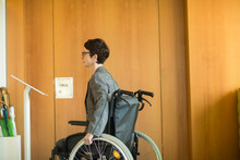 Woman In Wheelchair, Reading Sign At Office Entrance