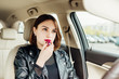 Businesswoman looking in rear view mirror and putting make up in car