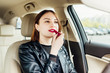Fashion woman making up her lips with red lipstick in car