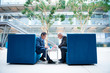 © Connect Images - Two businessmen having discussion meeting in office atrium armchairs