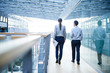 © Connect Images - Rear view of businessman and woman walking on office balcony