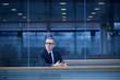 © Connect Images - Businessman with smartphone looking out from office balcony