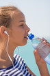 © polinabelphoto - Sports girl drinks water during a workout on the beach. The girl drinks water during fitness outdoors