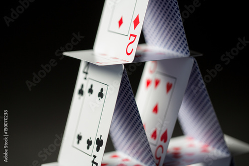 close up of house of playing cards over black плакат