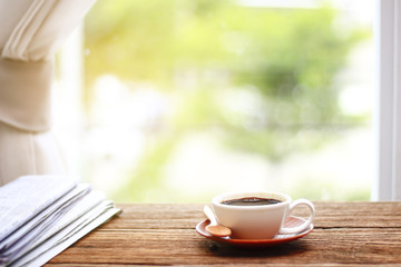 Wall Mural - Morning coffee, Cup of coffee with newspapers, near the window.background in the morning sunlight.