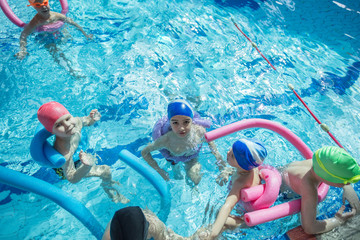 Wall Mural - happy children kids group at swimming pool class learning to swim