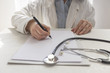 Medical doctor on white background with the stethoscope, looking at medical form and taking notes. Focus on the stethoscope and notes.