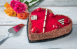 Erdbeerkuchen in Herzform mit Rosen auf weißem Holztisch zum Valentinstag oder Muttertag