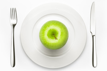 Diet concept, green apple on a white plate, fork, knife, weight loss, healthy diet