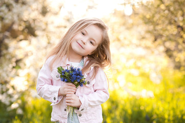 Wall Mural - Cute baby girl 5-6 year old holding flowers outdoors. Looking at camera. Childhood. Springtime.