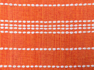 Close up of orange fabric pattern details with white dashed lines parallel