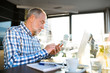 © Halfpoint - Senior businessman with smartphone and laptop in cafe