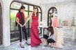 © Bavorndej - Cheerful skilled clothes asian designer team is serving her customer, She is standing near a woman in dress and measuring the size, She is holding a tape-line with concentrate.