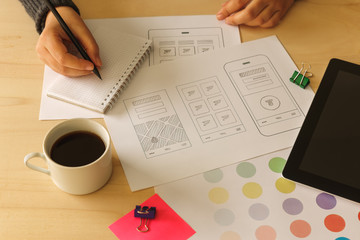 Wall Mural - Designer drawing mobile App wireframe sketches on wooden desk