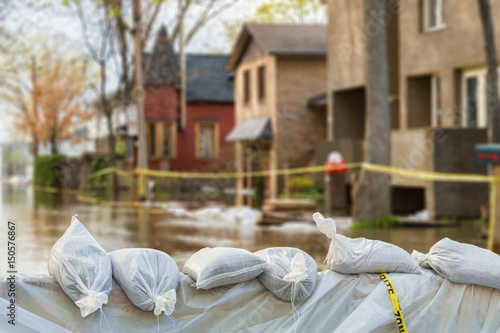 Fotomural Close shot of flood Protection Sandbags with flooded homes in the background
