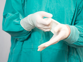 Doctor putting on white sterilized surgical glove