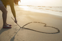 Beautiful Woman Writing Message (heart Symbol) On Sand Beach.