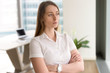 © fizkes - Pensive businesswoman standing with arms crossed in modern office interior. Female entrepreneur looks out of window into the distance, thinking about solution. Female leader concept