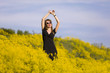© ginkgofoto - Young woman standing in a field of yellow flowers