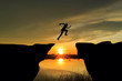 © comenoch - Man jumping over cliff on sunset background,Business concept idea