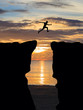 © comenoch - Man jumping over cliff on sunset background,Business concept idea